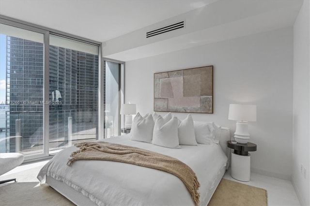 bedroom featuring baseboards, visible vents, and floor to ceiling windows