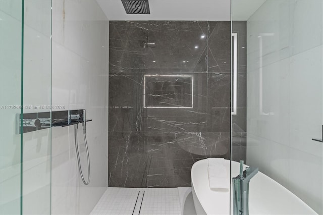 full bathroom with a freestanding tub, a marble finish shower, and tile walls