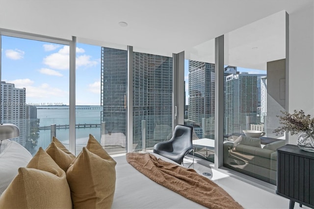 bedroom with a water view, access to exterior, a wall of windows, and a city view