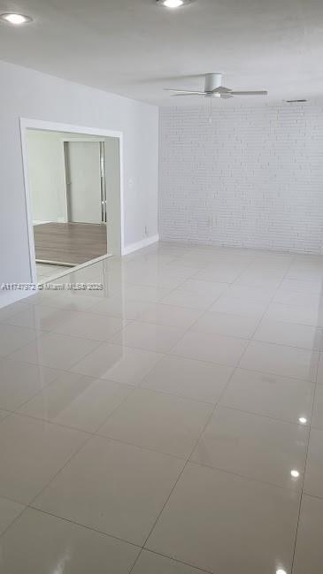 unfurnished room featuring brick wall and light tile patterned floors