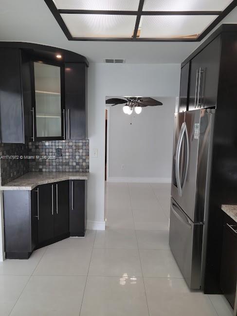 kitchen featuring tasteful backsplash, visible vents, stainless steel refrigerator with ice dispenser, and dark cabinets