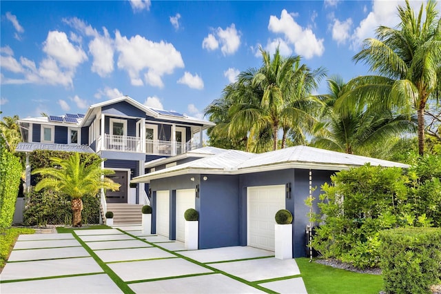 view of front of home featuring a garage, solar panels, a balcony, and stucco siding