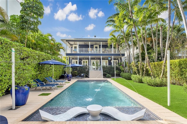 back of property featuring a yard, a patio, a ceiling fan, a balcony, and an outdoor pool