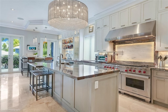 755 NE 77th St, Miami, FL 33138 - kitchen featuring dark stone counters, under cabinet range hood, decorative backsplash, a breakfast bar area, and luxury range