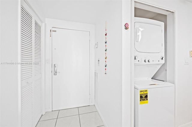 clothes washing area featuring light tile patterned floors and stacked washing maching and dryer