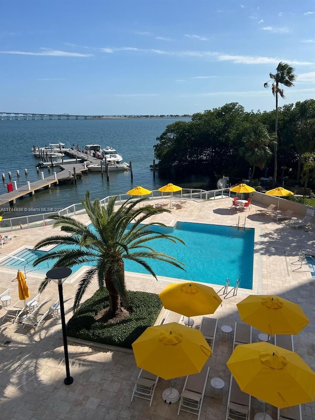 community pool featuring a patio area, fence, and a water view