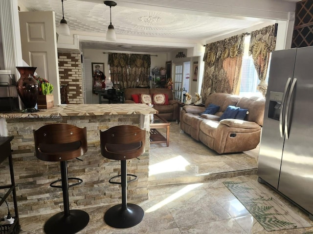 bar featuring hanging light fixtures and stainless steel fridge