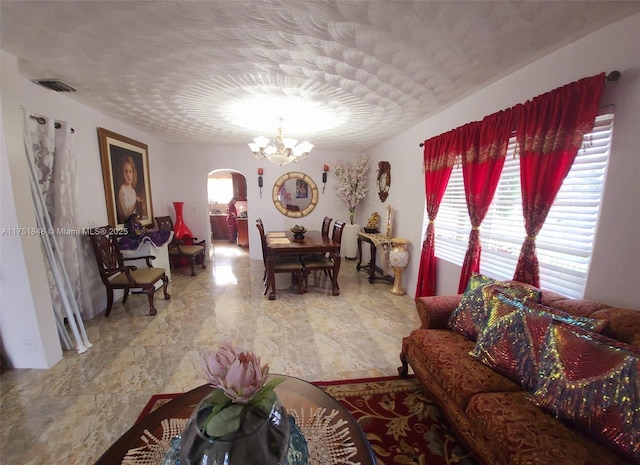 living room featuring visible vents, a textured ceiling, arched walkways, and a notable chandelier