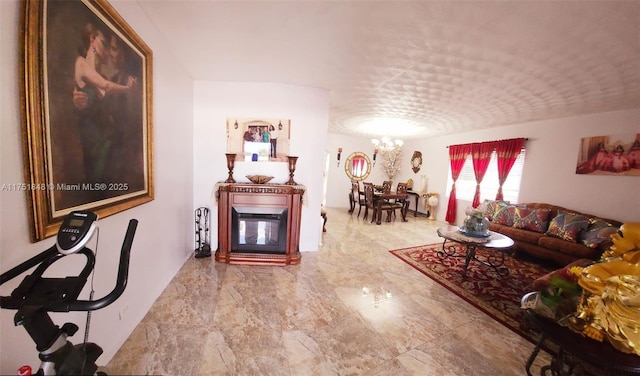 living room with a glass covered fireplace, marble finish floor, and a notable chandelier