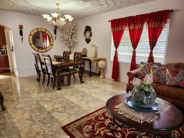 dining area featuring arched walkways, a notable chandelier, and a textured ceiling