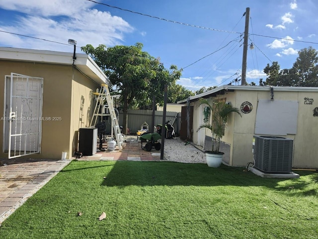 view of yard with a patio area, fence, and central AC