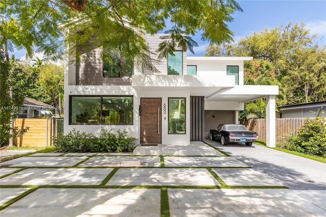 contemporary house with stucco siding, driveway, and fence