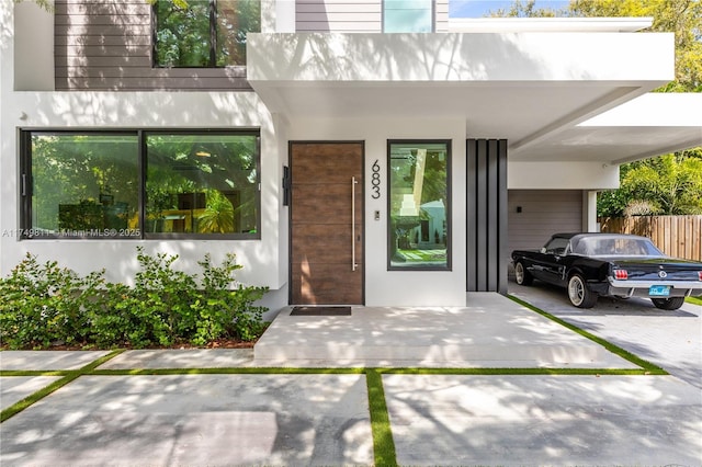 view of exterior entry featuring an attached carport and stucco siding