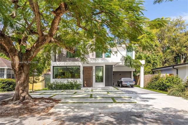 view of front facade featuring concrete driveway and fence