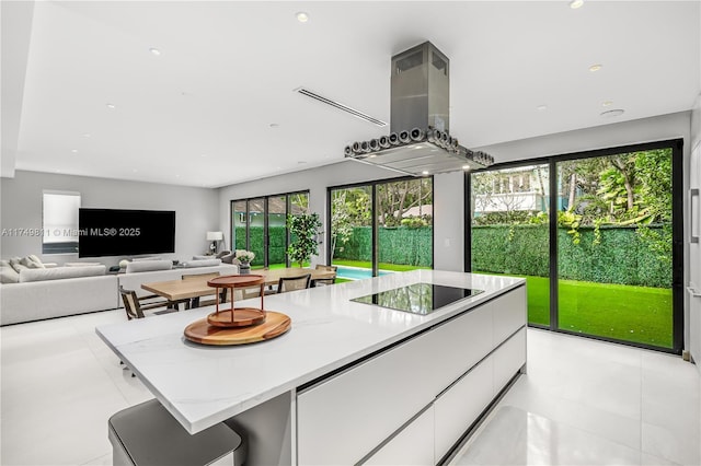 kitchen featuring light stone counters, black electric stovetop, open floor plan, white cabinets, and island range hood