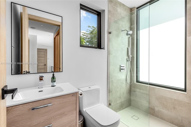 full bathroom with tiled shower, vanity, and toilet