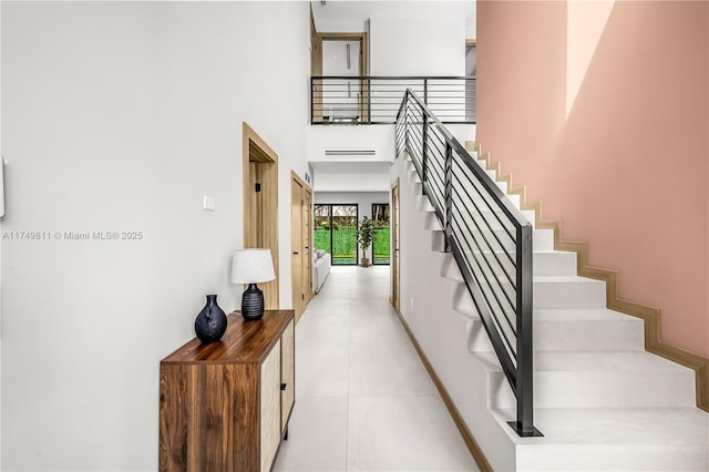 stairway featuring a towering ceiling and baseboards