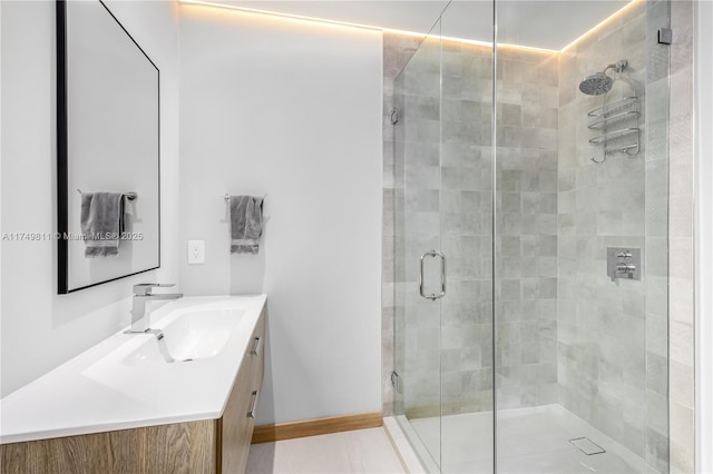 bathroom with a stall shower, vanity, and baseboards