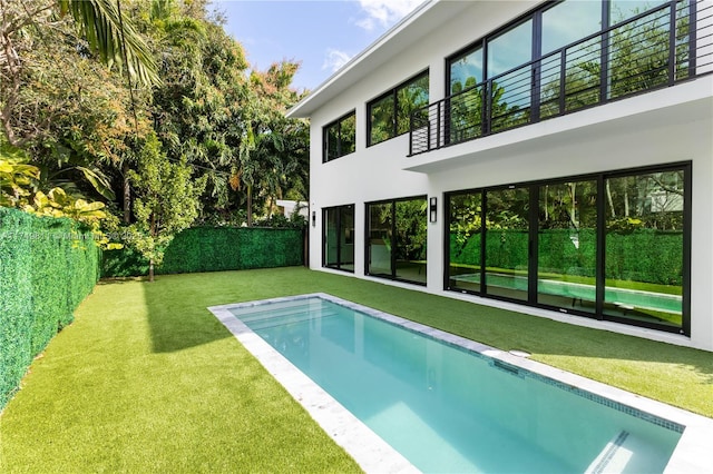 pool with a fenced backyard and a lawn