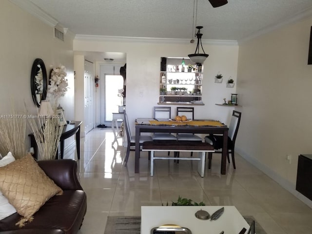 tiled dining room featuring a textured ceiling, baseboards, visible vents, and crown molding