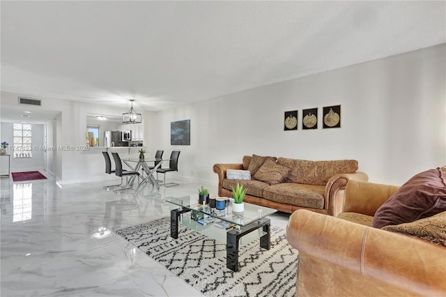 living area featuring baseboards, visible vents, marble finish floor, a textured ceiling, and a notable chandelier