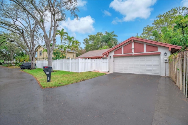 garage featuring aphalt driveway and fence