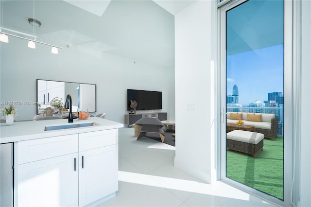 interior space with light tile patterned floors, a sink, white cabinets, light countertops, and track lighting