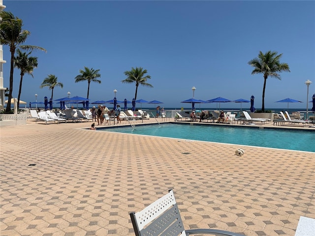 view of pool featuring a water view and a patio area