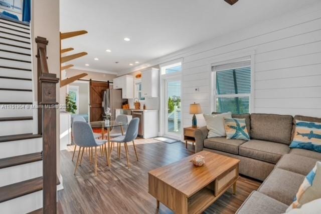 living room featuring recessed lighting, wood finished floors, stairway, and a barn door