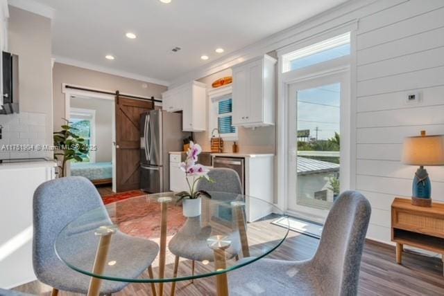 dining area with recessed lighting, light wood-style flooring, and a barn door