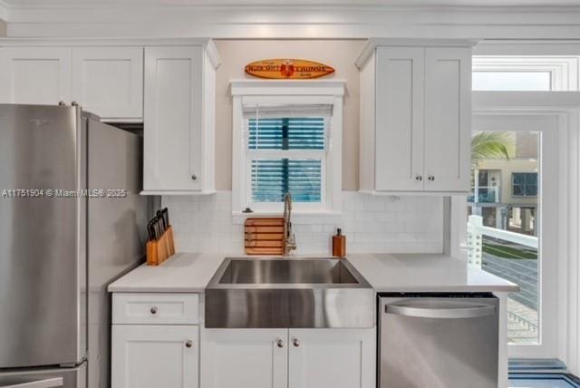 kitchen with appliances with stainless steel finishes, light countertops, white cabinets, and a sink