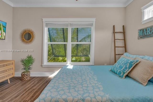 bedroom featuring baseboards, ornamental molding, and wood finished floors