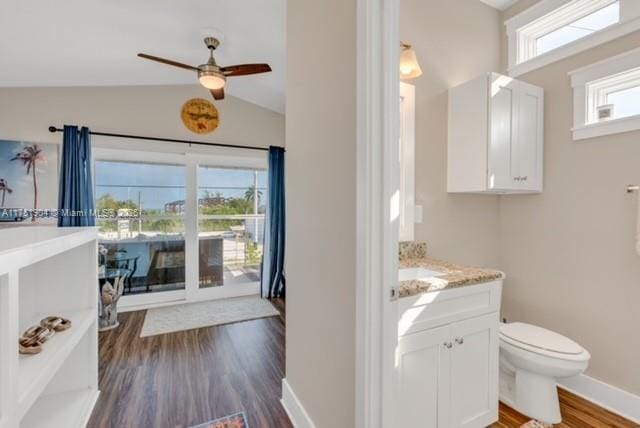 bathroom featuring baseboards, toilet, wood finished floors, vaulted ceiling, and vanity