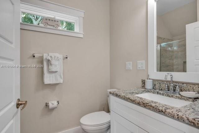 bathroom with toilet, a shower stall, baseboards, and vanity