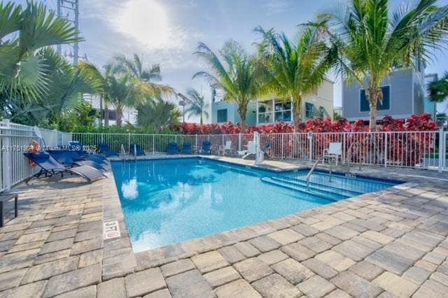 community pool with fence and a patio