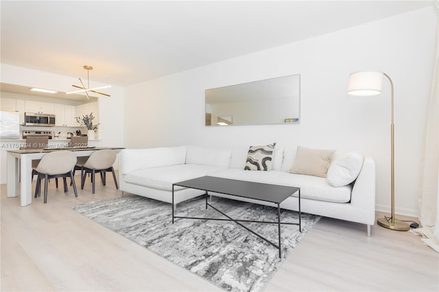 living room with light wood-type flooring and a chandelier