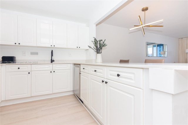 kitchen featuring light countertops, hanging light fixtures, light wood-style flooring, white cabinets, and a sink