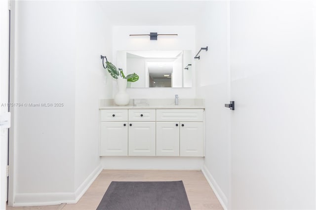 bathroom with wood finished floors, vanity, and baseboards