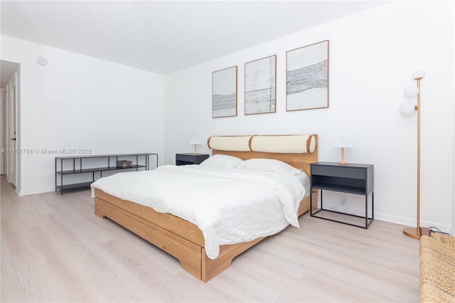 bedroom featuring light wood finished floors and baseboards