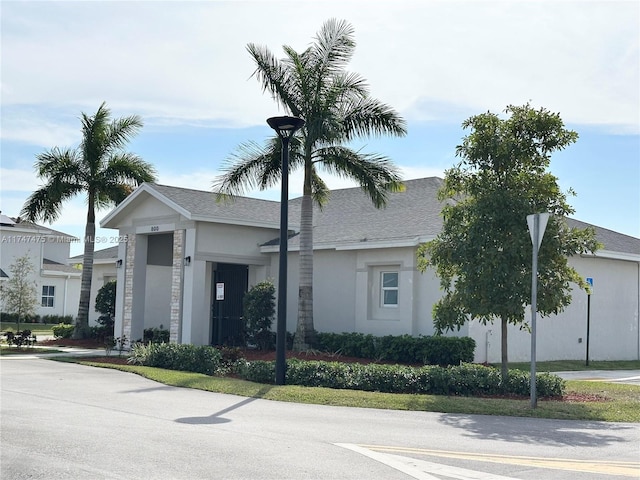 view of front of property featuring roof with shingles and stucco siding