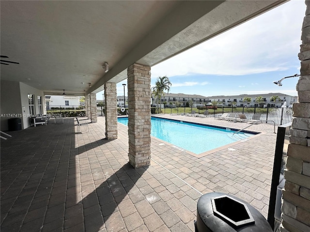 community pool with a patio area, ceiling fan, and fence