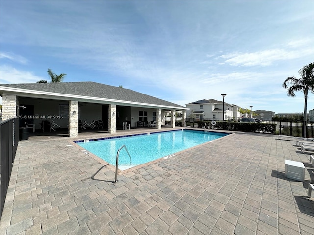 pool with a patio area and fence