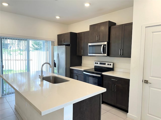 kitchen featuring stainless steel appliances, light countertops, a sink, an island with sink, and dark brown cabinets