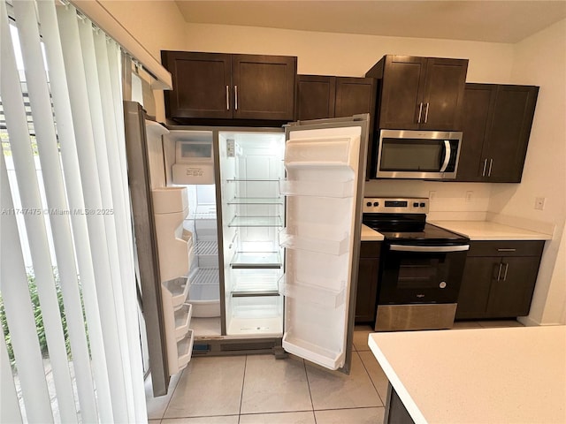 kitchen with appliances with stainless steel finishes, light countertops, dark brown cabinets, and light tile patterned floors