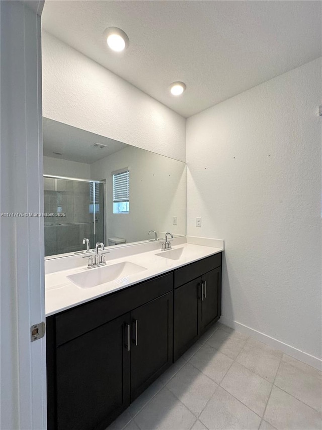 bathroom with a sink, a shower stall, baseboards, and double vanity