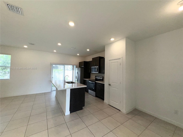 kitchen featuring a kitchen island with sink, visible vents, light countertops, appliances with stainless steel finishes, and dark cabinetry