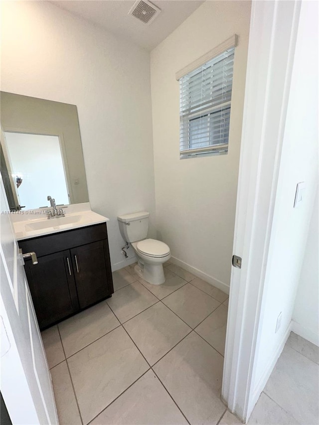 bathroom with toilet, vanity, baseboards, visible vents, and tile patterned floors