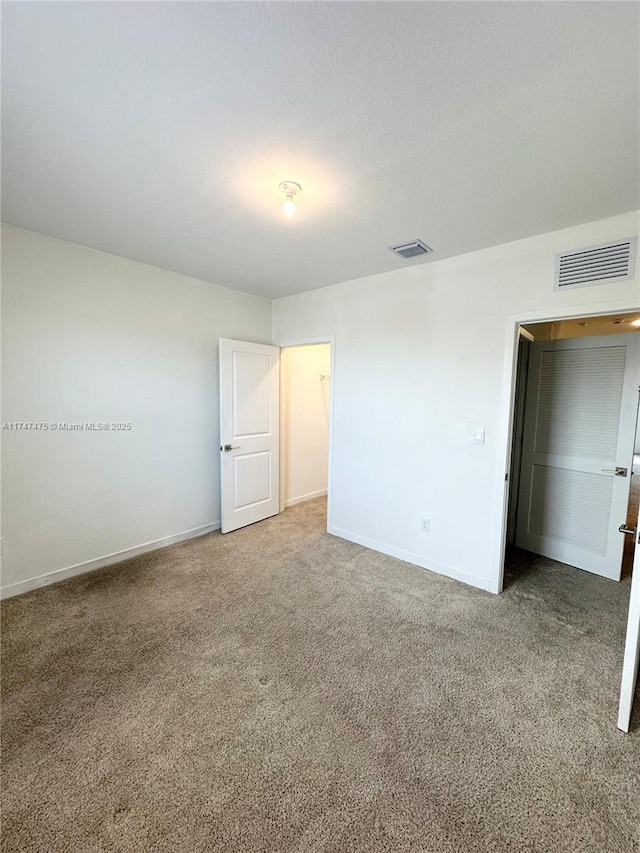 unfurnished bedroom featuring baseboards, visible vents, and carpet flooring