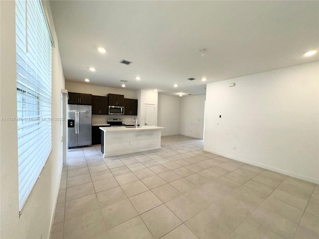 kitchen featuring recessed lighting, stainless steel appliances, open floor plan, light countertops, and a center island with sink