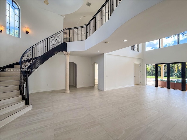 interior space featuring arched walkways, french doors, stairway, a high ceiling, and baseboards